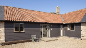 A building with a tiled roof, a brick chimney, and a gravel driveway. - Stylish cottage, courtyard views, countryside location, 20 mins to Cambridge (Royston)