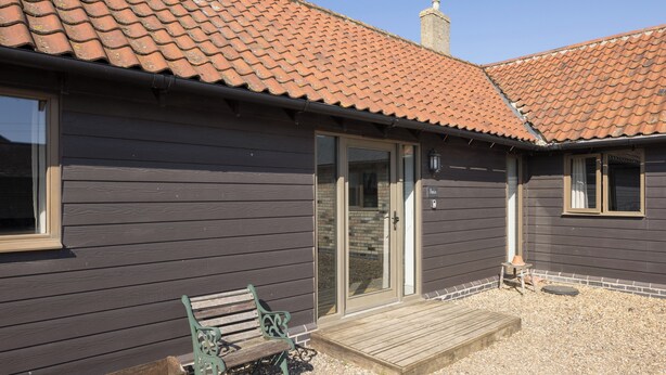 A house with a tiled roof, a wooden deck, and a bench. - Stylish cottage, courtyard views, countryside location, 20 mins to Cambridge (Royston)