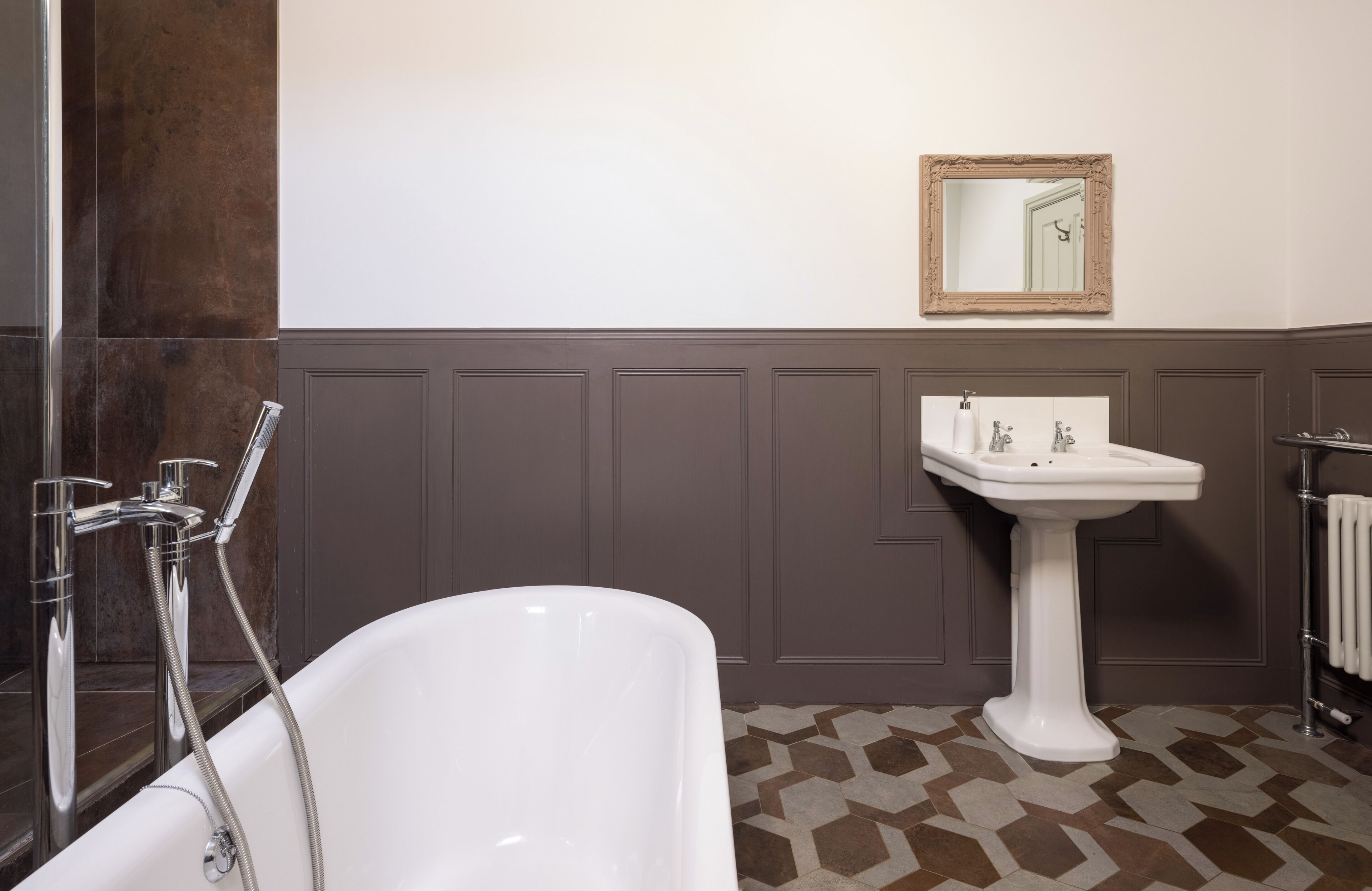 Ein Badezimmer mit einer freistehenden Badewanne, einem Standwaschbecken und einem Spiegel an der Wand.