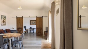 Un'ampia zona pranzo con tavolo e sedie in legno, una porta scorrevole a griglia e vista sul soggiorno.