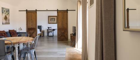 A spacious dining area with a wooden table and chairs, a sliding barn door, and a view of the living room.
