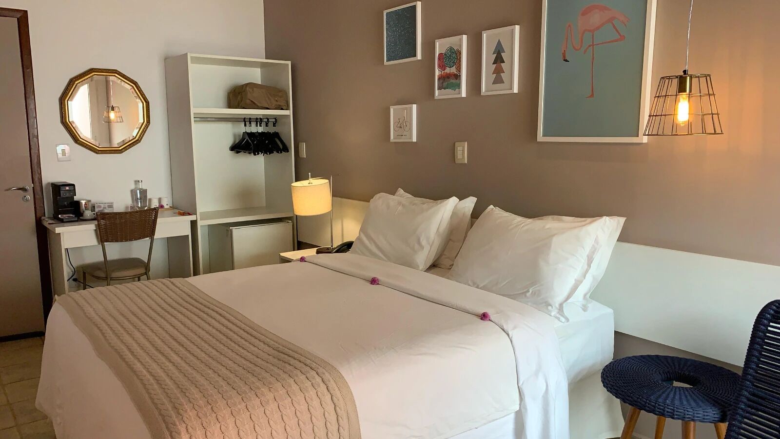 Una habitación de hotel con una cama, un escritorio, una silla, una lámpara y decoración en la pared.