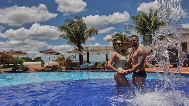 A swimming pool with clear blue water, surrounded by lounge chairs and umbrellas. - Frangipani Hotel Boutique (Brotas)