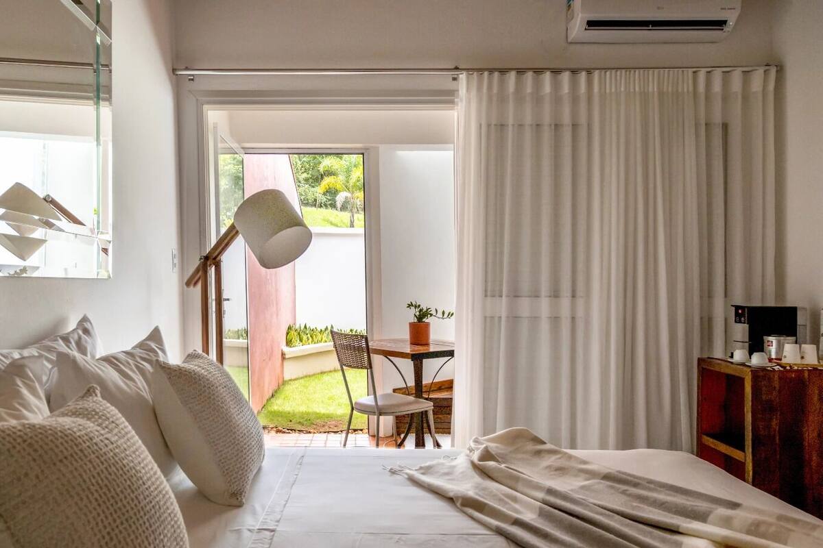 Une chambre à coucher avec un lit, un bureau et une chaise. Il y a une fenêtre et une porte qui donne sur un balcon.