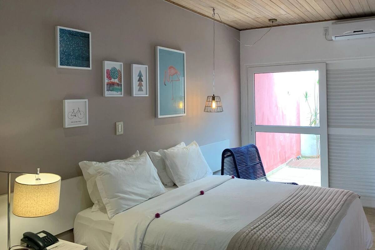 Une chambre à coucher avec un lit, une lampe et des œuvres d’art murales.