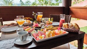 A breakfast buffet with various fruits, pastries, and beverages on a wooden table. - Frangipani Hotel Boutique (Brotas)
