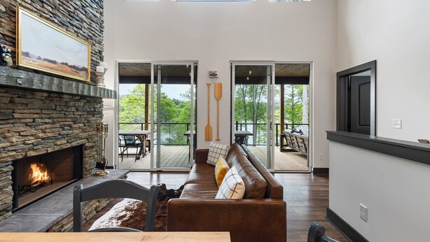 A modern living room with a stone fireplace, a leather sofa, and a dining table.