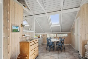 A room with a wooden interior, a dining table with chairs, a window, and a skylight.