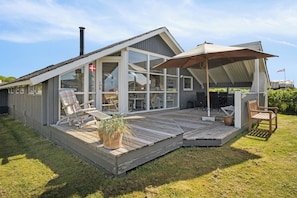 A modern house with a large deck, a chimney, and a flag.