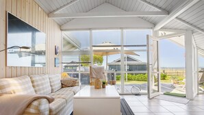A room with a checkered sofa, a white coffee table, and a view of the outdoors through large glass doors.