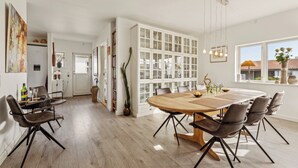 A dining area with a round table, chairs, and a cabinet with glass doors. - Sea and meadow views – space and calm (Nyborg)