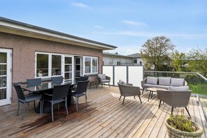A deck with outdoor furniture, a glass table, and a potted plant.