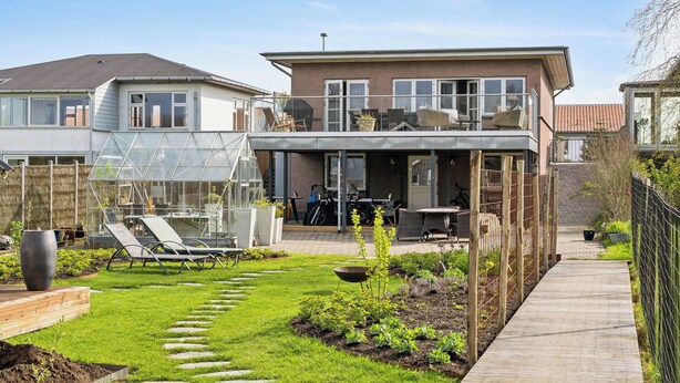 A two-story house with a balcony, a garden with stepping stones, and a clear sky. - Sea and meadow views – space and calm (Nyborg)