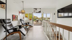 A modern interior with a view to the outdoors, featuring leather chairs, a wooden table, and a staircase. - Sea and meadow views – space and calm (Nyborg)