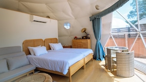A modern bedroom with a large bed, a sofa, a small table, and a wicker chair. - Gramercy Village Yamanakako (Yamanakako)