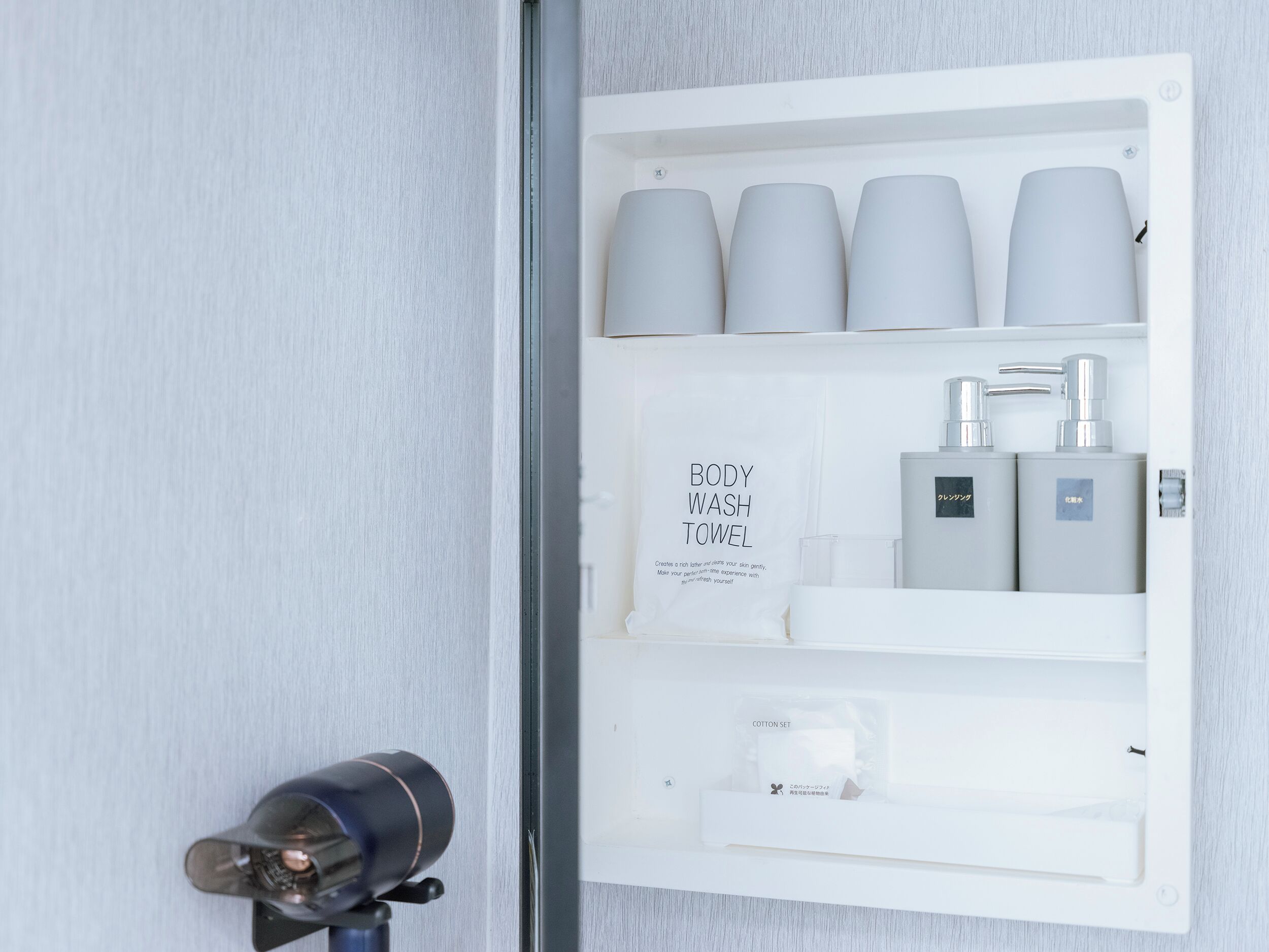 A bathroom with a white towel dispenser, a body wash towel, and a cotton set.