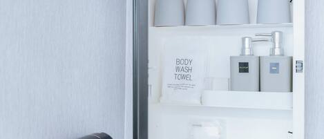 A bathroom with a white towel dispenser, a body wash towel, and a cotton set.