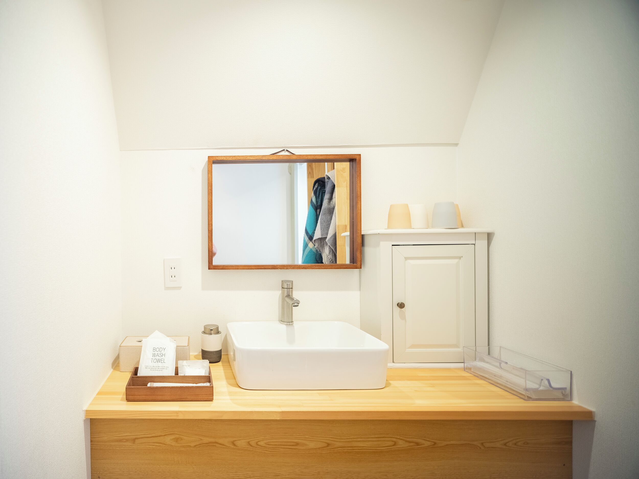 A bathroom with a white sink, a mirror, a towel rack, and a cabinet.
