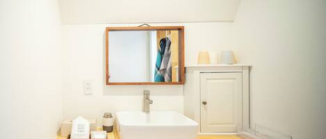 A bathroom with a white sink, a mirror, a towel rack, and a cabinet.