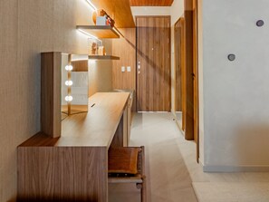 A modern interior with a wooden vanity, mirror with lights, and a bench. - NANNAI Milagres (Passo de Camaragibe)