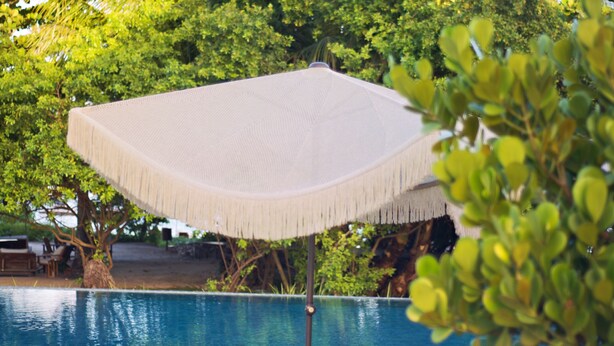 A poolside area with two lounge chairs and a woven umbrella. - NANNAI Milagres (Passo de Camaragibe)