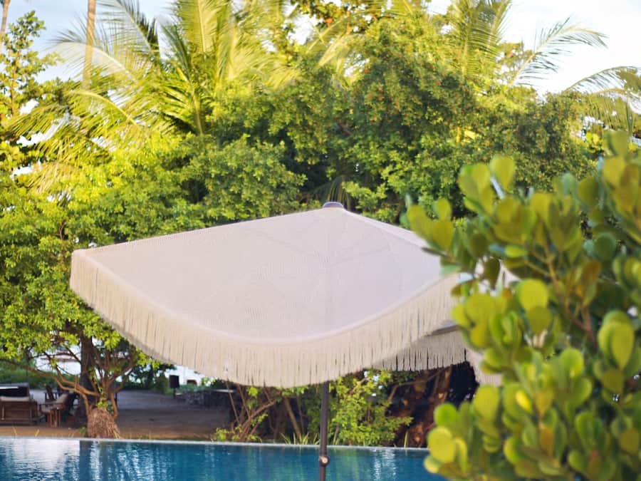 A poolside area with two lounge chairs and a woven umbrella.