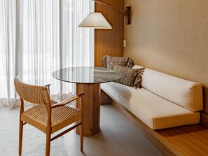 A room with a round glass table, a woven chair, a sofa with cushions, and a wall-mounted lamp. - NANNAI Milagres (Passo de Camaragibe)