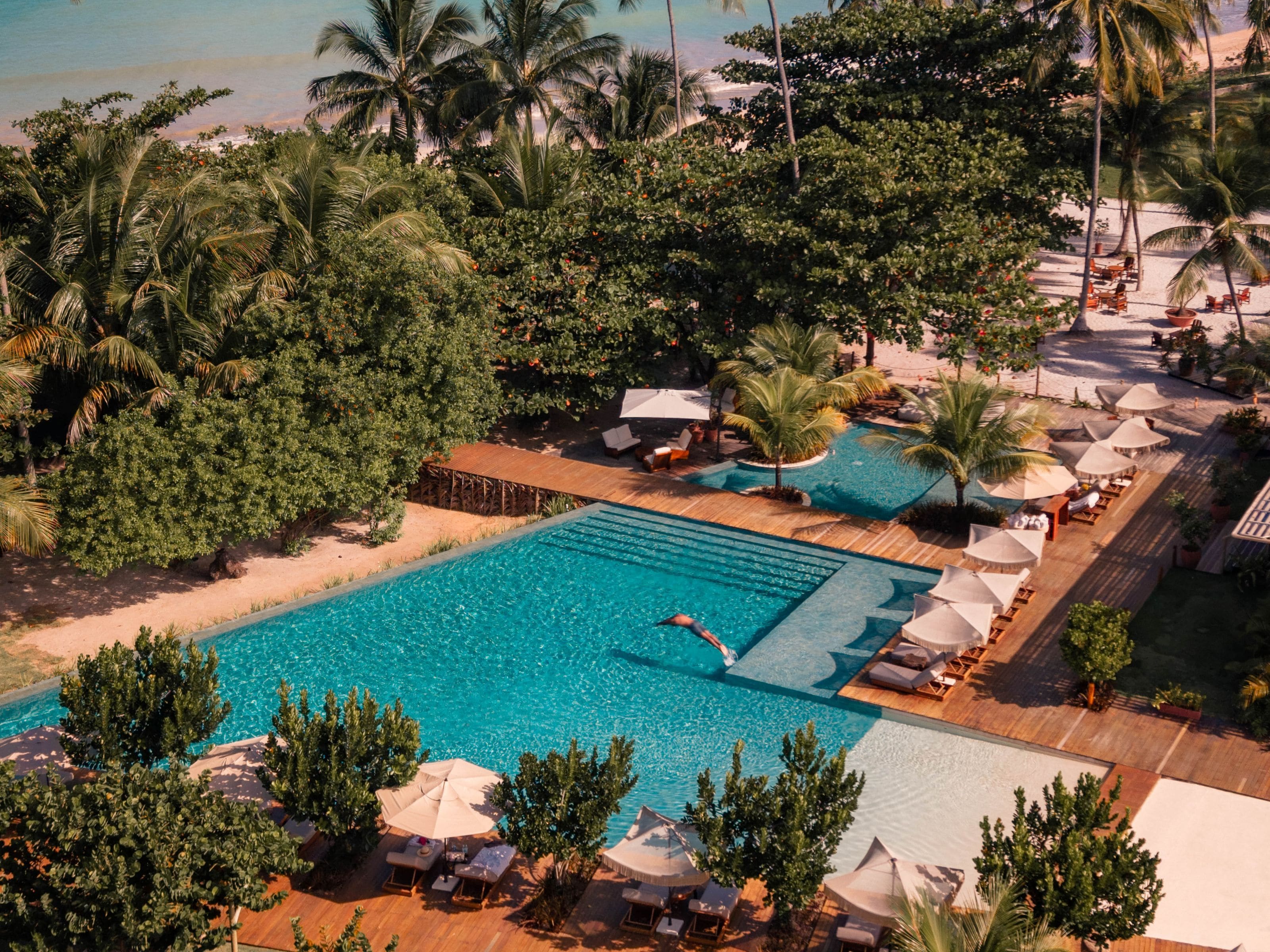 Un resort con piscina, zonas de descanso y palmeras.