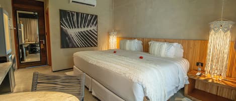A hotel room with a large bed, a bedside table, a mirror, a wall-mounted air conditioner, and a modern light fixture.