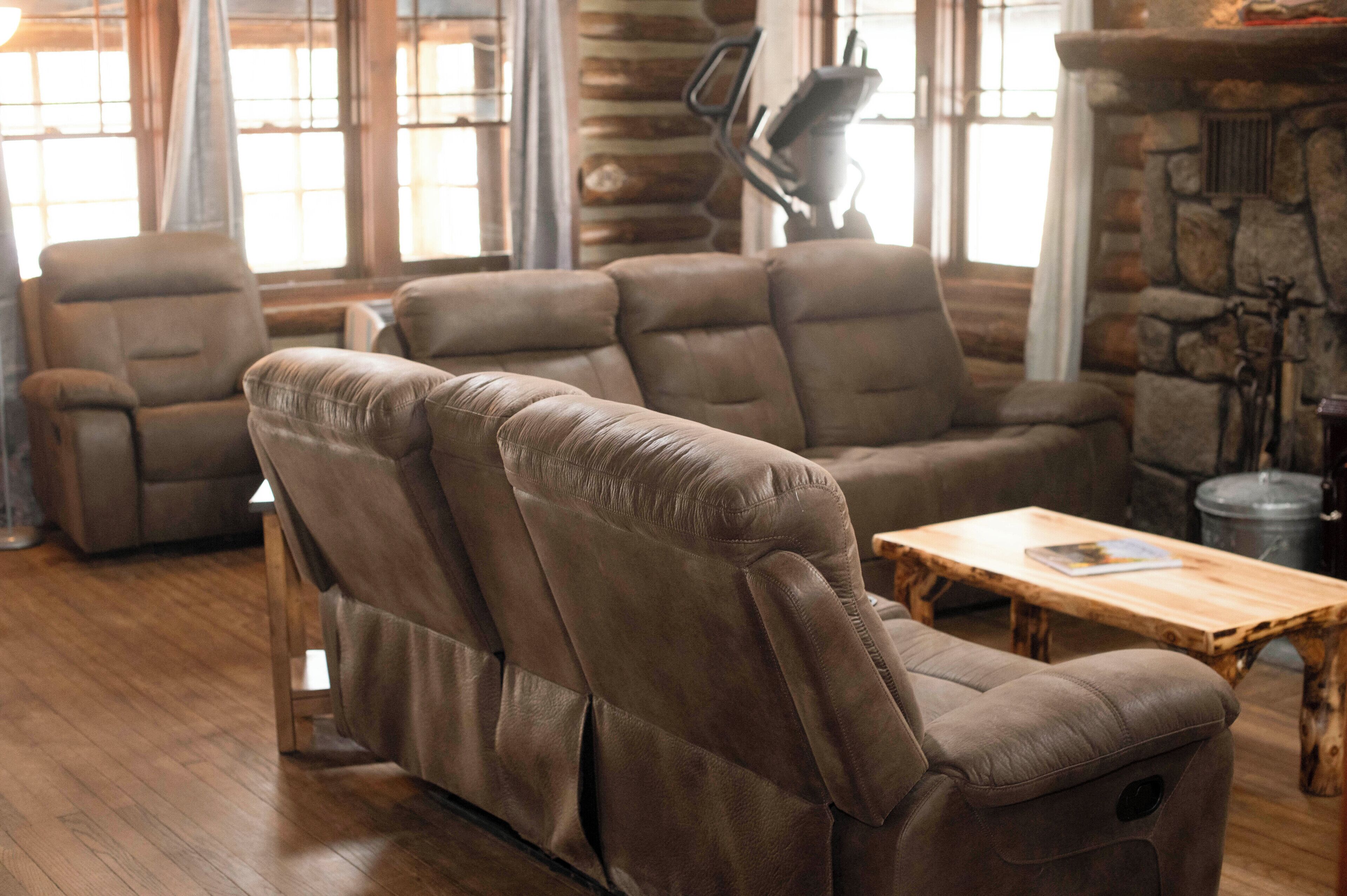 A living room with a sectional sofa, a wooden coffee table, and a stone fireplace.