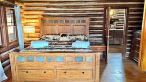 Une chambre dans une cabane en rondins, avec un lit en bois, une table de chevet avec une lampe et une commode.