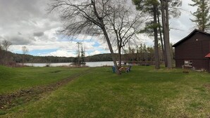 Un espace verdoyant avec un lac, un chalet en bois et un véhicule de golf.