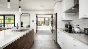 A modern kitchen with white cabinets, a large island, and a view to the outside. - Modern Desert Oasis - Shuffleboard, Hiking, Pool & Putting green! (Phoenix)