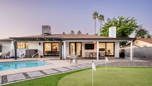 A modern house with a swimming pool, patio, and a well-maintained lawn. - Modern Desert Oasis - Shuffleboard, Hiking, Pool & Putting green! (Phoenix)