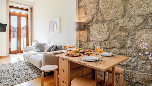 Un comedor con pared de piedra, mesa de madera y sillas.