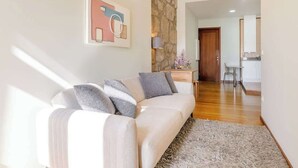 Una sala de estar moderna con un sofá, una pared de acento de piedra y vistas a la cocina.