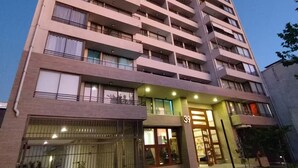 A high-rise residential building with multiple balconies, a gated entrance, and a well-lit ground floor.