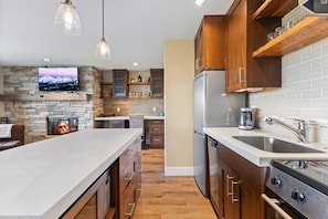 Una cocina moderna con chimenea de piedra, armarios de madera y electrodomésticos de acero inoxidable, además de una isla grande.