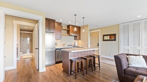 A modern kitchen with wooden cabinets, a central island with stools, and a built-in oven.