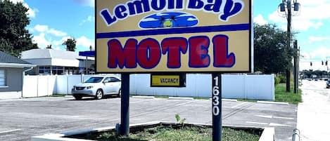 Een motelbord met de naam 'Lemon Bay Motel' en een 'VACANT' bordje eronder.