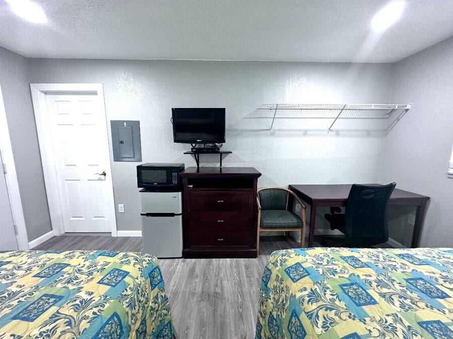 Quarto de hotel com duas camas, uma mesa de escritório, televisão, frigorífico e micro-ondas.