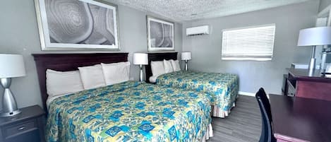 A hotel room with two beds, a desk, and a chair.