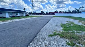 Straßenansicht mit einem Motel, einem Parkplatz und einem eingezäunten Bereich.
