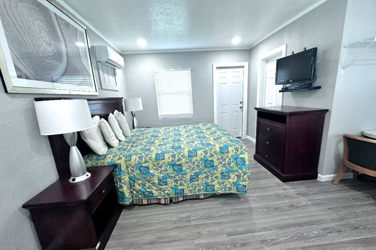 A bedroom with a bed, bedside tables, a TV, and a wardrobe.