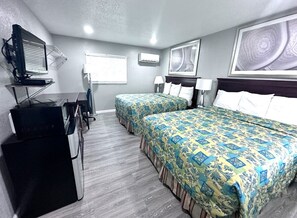A hotel room with two beds, a desk with a computer, a TV, and artwork on the walls. - Lemon Bay Motel (Englewood)