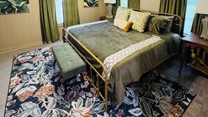 A bedroom with a bed, a bench, a ceiling fan, and a floral rug.