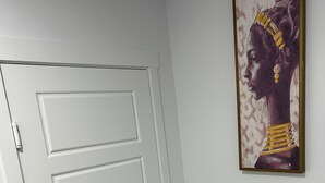 Una puerta blanca con una manija moderna, una obra de arte enmarcada en la pared y suelo de madera.