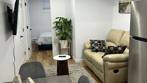Una sala de estar moderna con un sofá, una mesa de comedor y una zona de cocina con refrigerador.