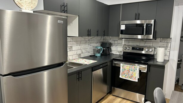 Una cocina moderna con electrodomésticos de acero inoxidable, salpicadero de mármol y suelo de madera.