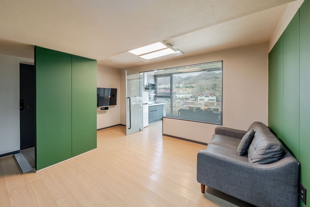 Una cocina moderna con un ventanal grande, televisor integrado y una pared de acento verde.